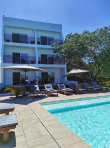 a hotel with chairs and umbrellas next to a swimming pool at Nosy Be Sun Hôtel in Nosy Be