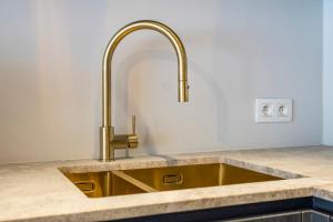 d'un évier avec un robinet en or. dans l'établissement Rustig, comfortabel app op 50meter van het strand, à Coxyde 11 autres photos