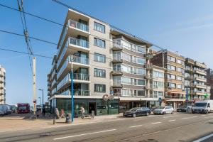 un grand immeuble d'appartements dans une rue de la ville avec des voitures dans l'établissement Rustig, comfortabel app op 50meter van het strand, à Coxyde