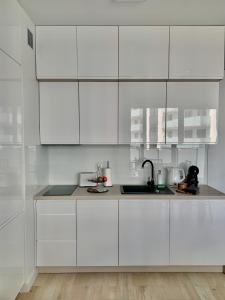 a white kitchen with white cabinets and a sink at REMAR - Apartments Lake Biale in Augustów