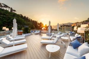a rooftop deck with white lounge chairs and tables at Carrick Hotel Camogli Portofino Coast in Camogli