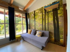 ein Sofa in einem Zimmer mit einem Wandbild von Bäumen in der Unterkunft Herberg Baton Rouge in Vielsalm