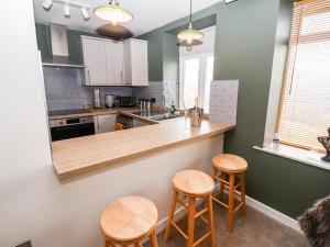 a kitchen with wooden counter tops and stools at The Carriage in Lydney