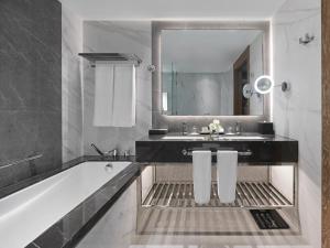 a bathroom with a tub and a sink and a mirror at Fairmont Dubai in Dubai