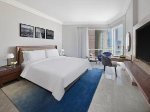 a bedroom with a large white bed and a tv at Fairmont Dubai in Dubai