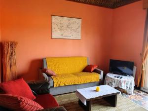 a living room with a yellow couch and a table at Villa du Port in Port-Vendres