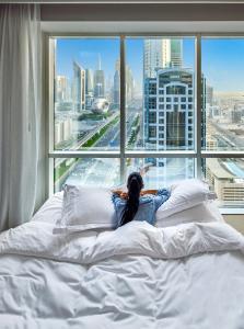 a woman laying on a bed in front of a window at Fairmont Dubai in Dubai