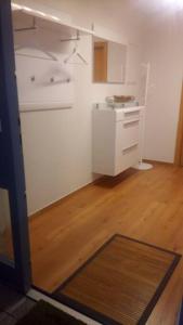 a kitchen with white cabinets and a wooden floor at Ferienwohnung DaWie in Öhringen