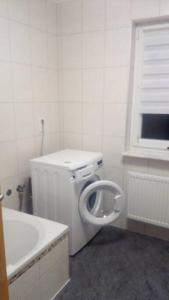 a white bathroom with a urinal and a bath tub at Ferienwohnung DaWie in Öhringen