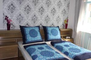 a bedroom with two beds with blue pillows and a wall at Ferienwohnung DaWie in Öhringen