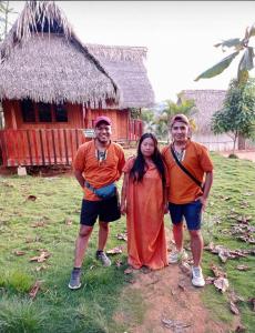 a group of three people standing in front of a hut at Victtorios Hotel in Satipo