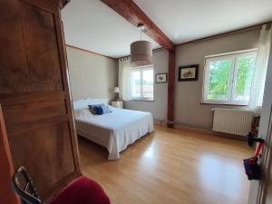 Un dormitorio con una cama blanca y dos ventanas. en Le Pressoir de Marsac, en Marsac