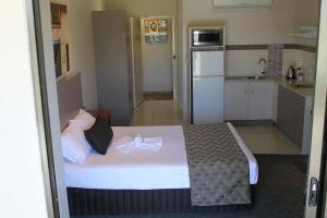 a bedroom with a large bed and a kitchen at Emerald Executive Apartments in Emerald