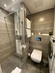 a bathroom with a toilet and a glass shower at Noir Silvery Apartman in Szeged