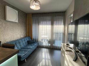 a living room with a blue couch and a table at Noir Silvery Apartman in Szeged