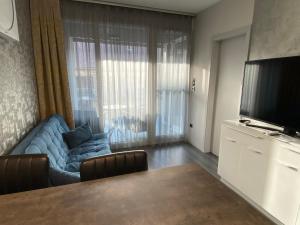 a living room with a blue couch and a television at Noir Silvery Apartman in Szeged