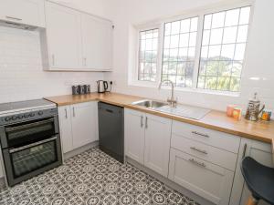 a kitchen with white cabinets and a sink at Seawinds 2a in Colwyn Bay
