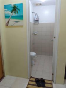 y baño con ducha, aseo y alfombra. en Guest House in Cainta Rizal, en Cainta