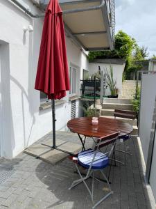 un parapluie rouge assis à côté d'une table et de chaises dans l'établissement Strandgut, à Sellin