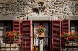 un edificio con persianas rojas y flores en la ventana en Villa Giarradea, en Cortona