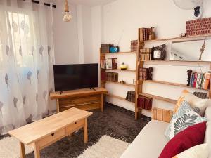 uma sala de estar com uma televisão de ecrã plano e um sofá em The Other Place em Lecrin