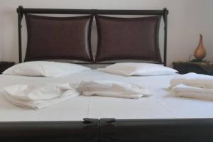 a bed with white sheets and pillows on it at Lovely 3-Bed House in Murties in Kalymnos