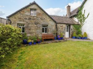 una vecchia casa in pietra con una panchina nel cortile di Inglis Nook Cottage a Lochearnhead