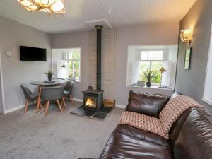 a living room with a couch and a table and a fireplace at Inglis Nook Cottage in Lochearnhead