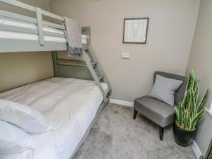 una camera da letto con un letto a castello e una sedia di Inglis Nook Cottage a Lochearnhead