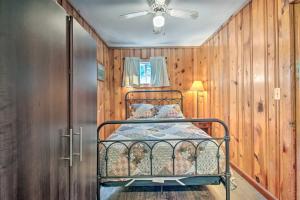 Cozy Newton Lake Cottage with View of the Lake! في Carbondale: غرفة نوم بسرير معدني في غرفة بجدران خشبية