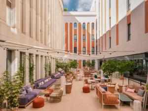 un patio extérieur avec des chaises et des tables dans un bâtiment dans l'établissement Ibis Styles Sevilla City Santa Justa, à Séville