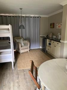 a living room with a bed and a table and a kitchen at Happy Lands Farmstay in Addo