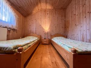 2 Betten in einem Zimmer mit Holzwänden in der Unterkunft Fenyves Home in Izvoare
