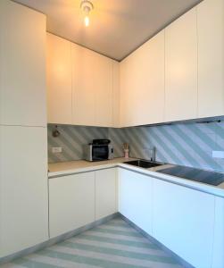 - une cuisine avec des placards blancs et un évier dans l'établissement Natante 38 - Immobiliare Living, à Lido di Jesolo