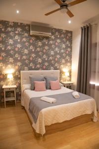 Un dormitorio con una cama con almohadas rosas. en El Hidalgo, en Almagro