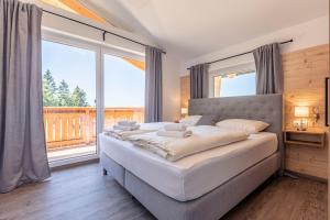 a bedroom with a large bed and a large window at Englmar Chalets by ALPS RESORTS in Sankt Englmar