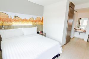 ein Schlafzimmer mit einem weißen Bett und einem Waschbecken in der Unterkunft GHL Hotel Neiva in Neiva