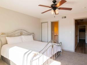 um quarto com uma cama branca e uma ventoinha de tecto em Moonlight Beach Villa em Pensacola Beach