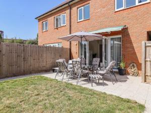 a patio with a table and chairs and an umbrella at Cheerful Townhouse in Sittingbourne