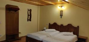 1 dormitorio con 2 camas y reloj en la pared en Pensiunea La Turcu, en Moieciu de Sus