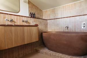 baño con bañera marrón y espejo en Capelongue, a Beaumier hotel & Spa, en Bonnieux