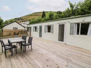 a wooden deck with a table and chairs on a house at Grange Caravan in Llangollen