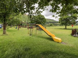 a playground with a yellow slide in a park at Grange Caravan in Llangollen