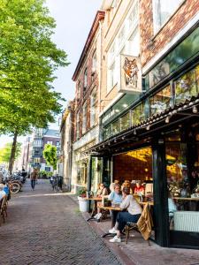 un grupo de personas sentadas en mesas fuera de una tienda en Wolf Hotel Kitchen & Bar, en Alkmaar