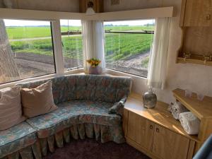 a living room with a couch and a large window at stacaravan Mientje in Hantum