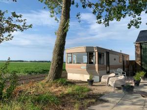 an rv parked next to a tree in a field at stacaravan Mientje in Hantum