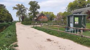 a dirt road next to a fence and a building at Hof an der Semkenfahrt - Adele in Worpswede