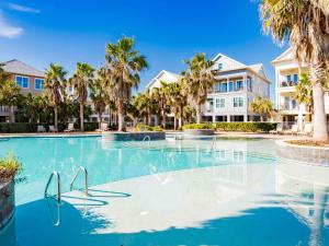 a swimming pool with palm trees and condos at Beach Music in Gulf Shores