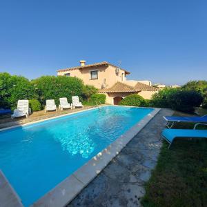 a swimming pool with chairs and a house in the background at Villa Picasso A in Stintino