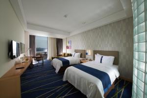 a hotel room with two beds and a television at Holiday Inn Express Zhengzhou Airport, an IHG Hotel in Xinzheng